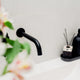a bathroom sink with a soap dispenser and a vase of flowers